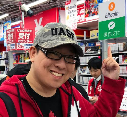 A man wearing a camouflage UASF hat and pointing to a Bitcoin payment sign in a store, capturing a moment of Bitcoin nostalgia during the 2017 civil war.